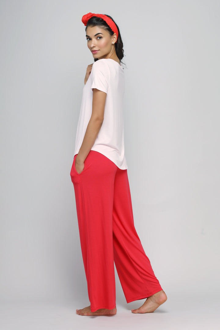 Model wearing a delicate blush top with coral pants, stylish and modern.