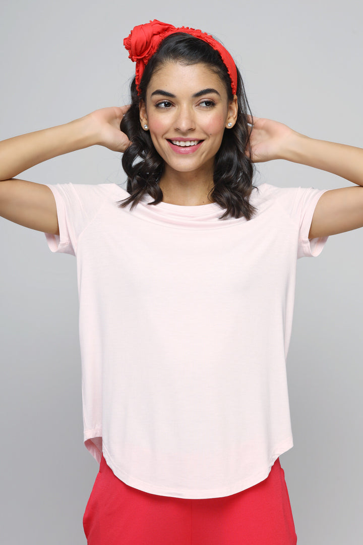 Smiling woman wearing a delicate blush top with red accessories.