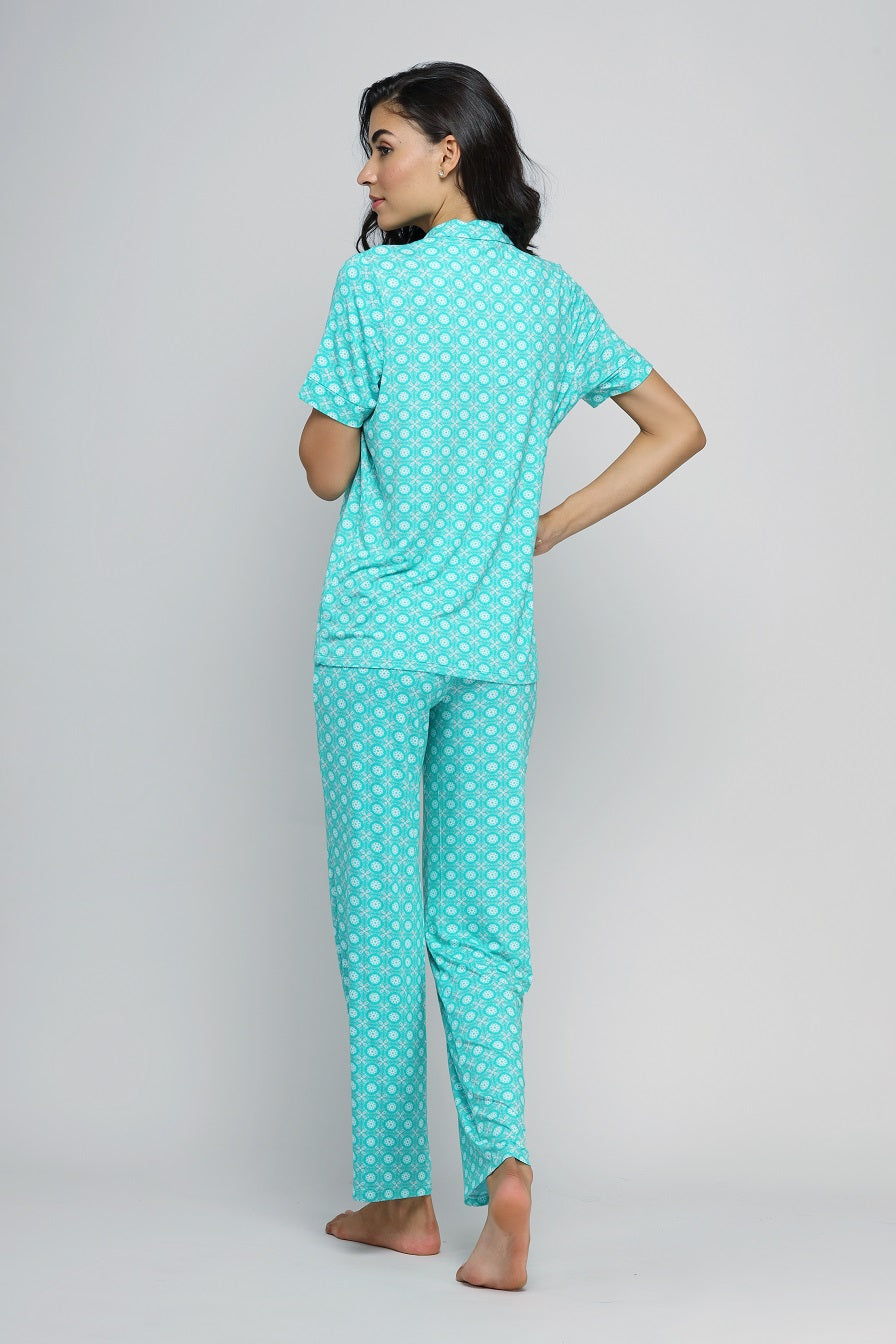 Woman wearing teal patterned button-down pajama set, showcasing back view.