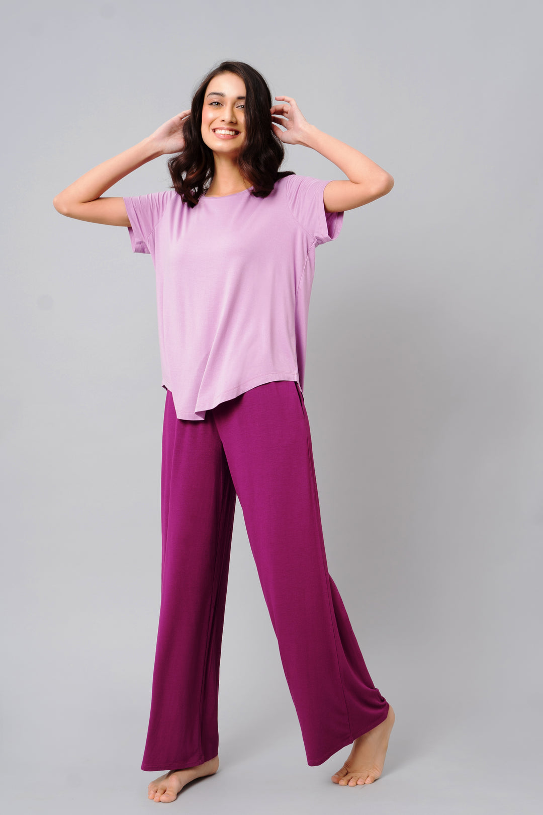 Smiling model wearing a soothing purple top and matching pants.