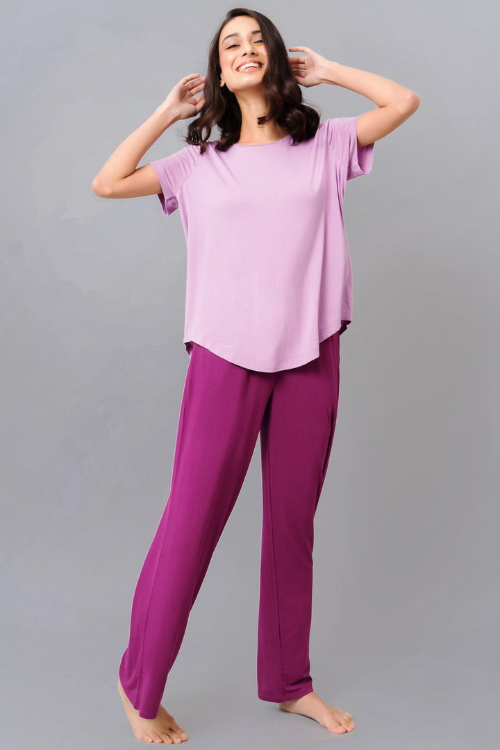 Woman in a soothing purple top and matching pants, smiling confidently.