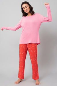 Model wearing Love Escape Pajamas, featuring pink top and printed red pants.