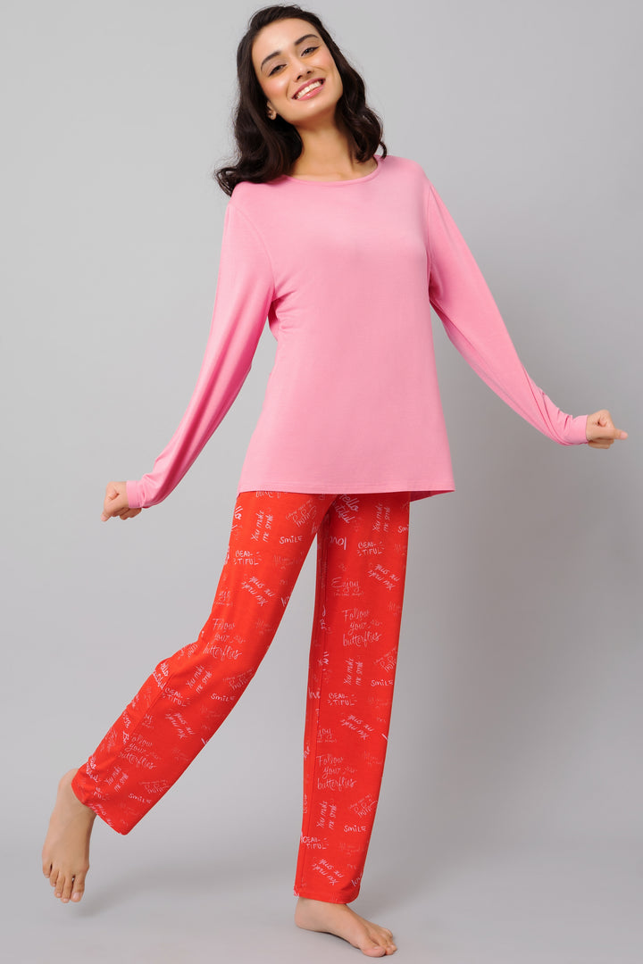 Model wearing Love Escape Pajamas with pink top and red patterned pants.