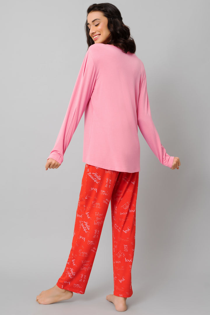 Woman wearing Love Escape Pajamas with pink top and red patterned pants.
