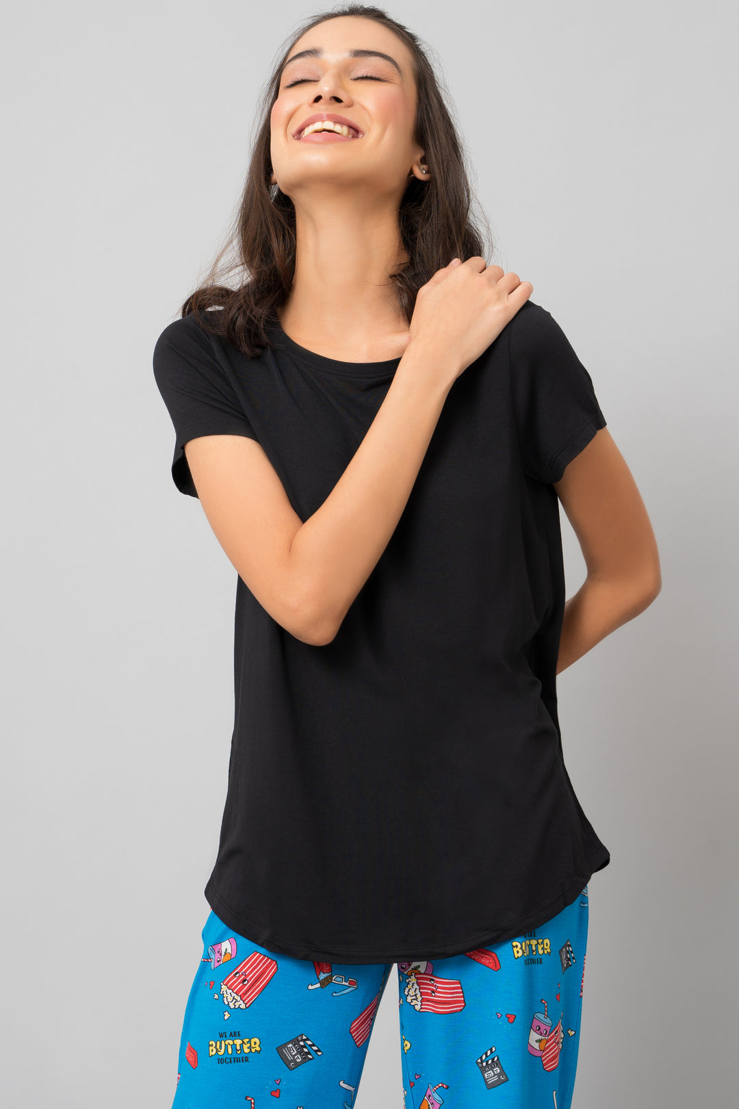 Smiling woman in black shorts set, vibrant pajama bottoms.