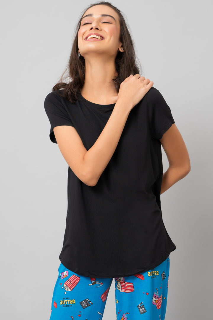 Smiling woman in black shorts set, vibrant pajama bottoms.