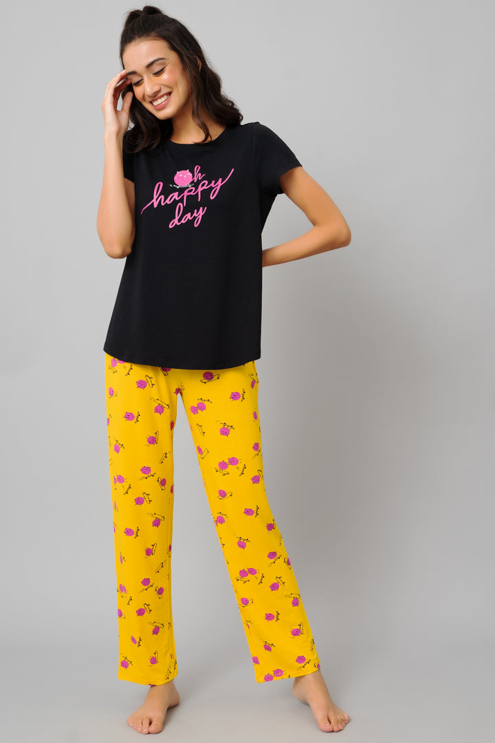 Happy woman modeling Fuffy Kitty Pajamas, black top and yellow floral pants.