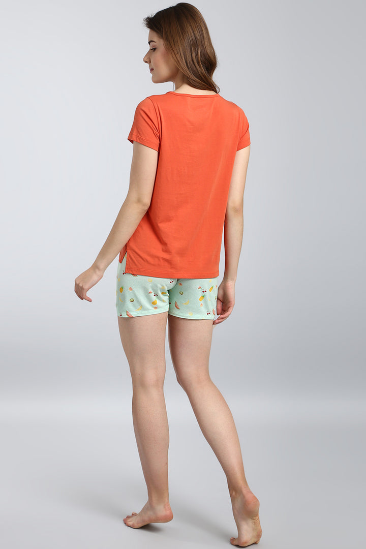 Woman wearing Berry Blast Shorts and an orange tee, stylish loungewear.