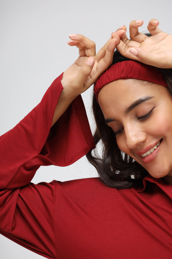 Smiling woman wearing a rhubarb long button-down top and headband.