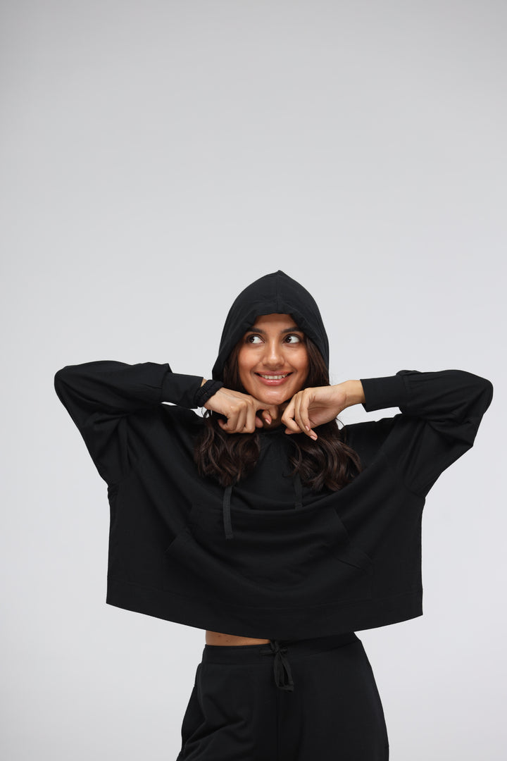 Smiling woman wearing a black Luxflo travel hoodie with a hood.