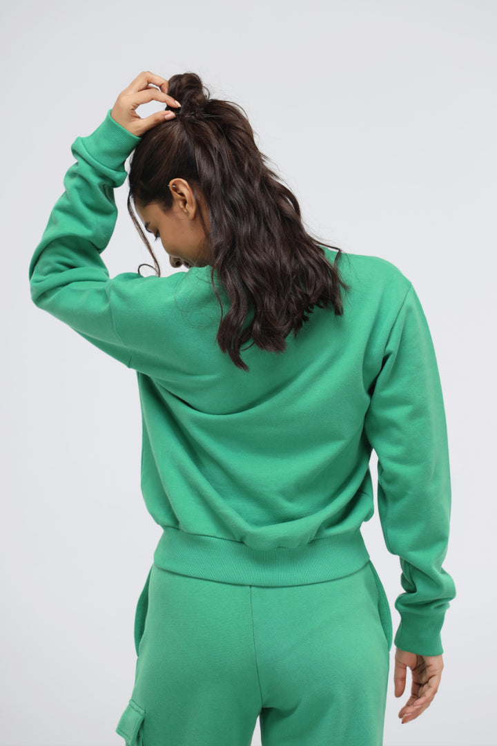 Woman wearing a green relaxed terry sweatshirt from the back.