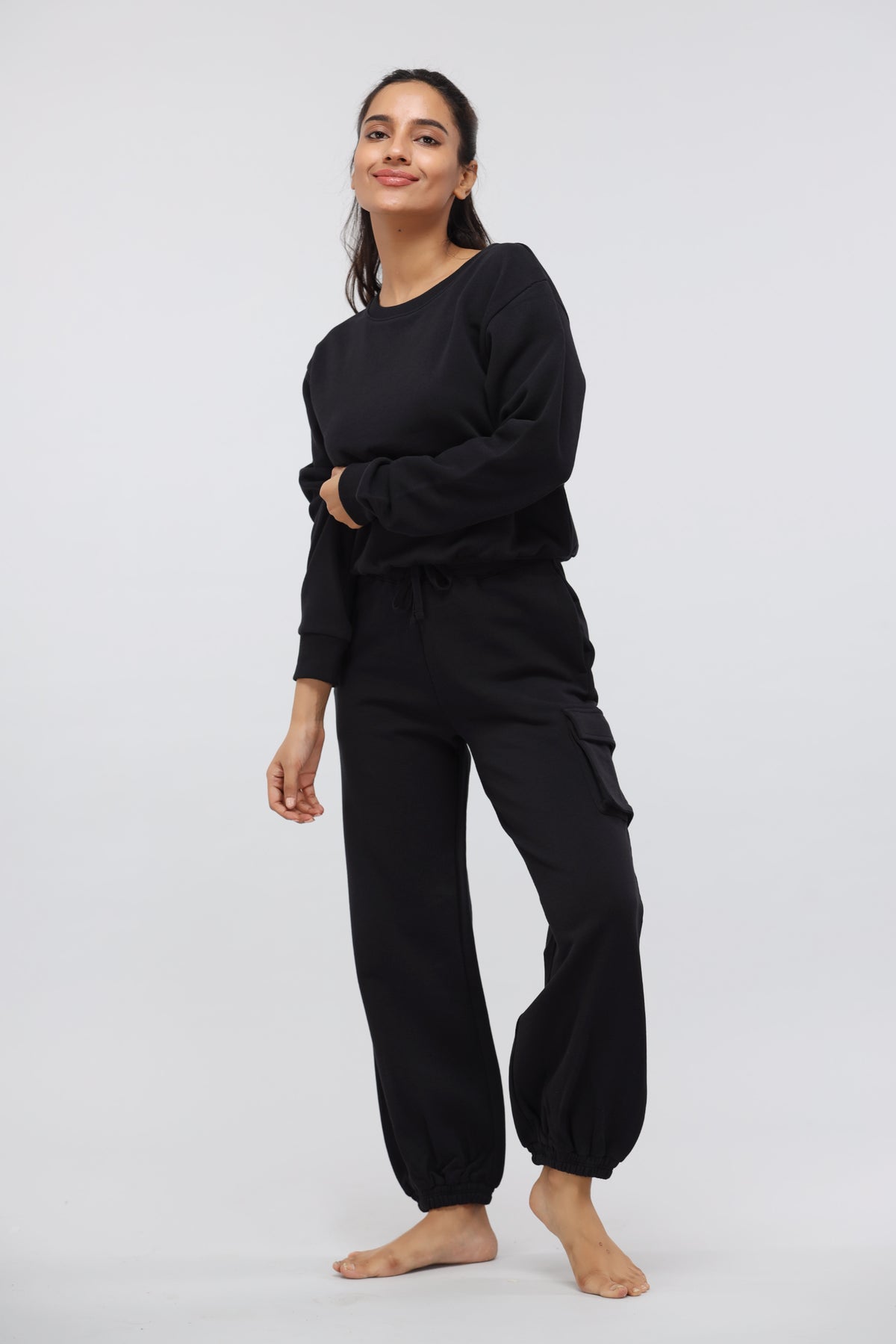 Woman modeling a jet black terry jogger set against a light background.