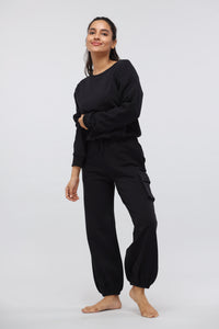 Woman modeling a jet black terry jogger set against a light background.