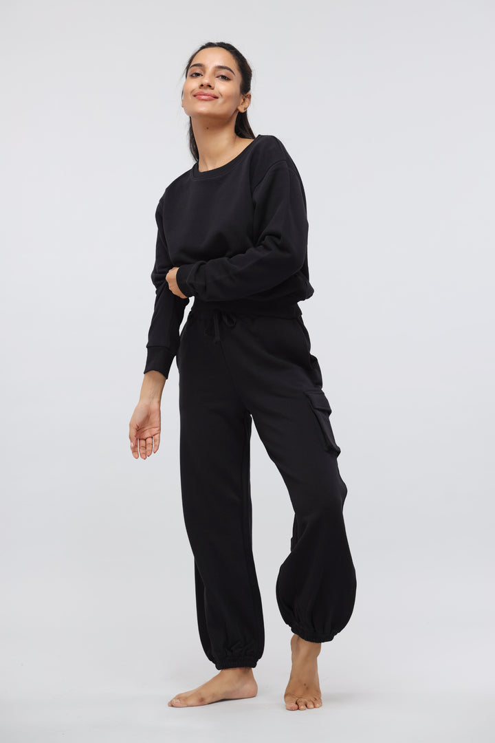 Model wearing a jet black relaxed sweatshirt with matching pants.