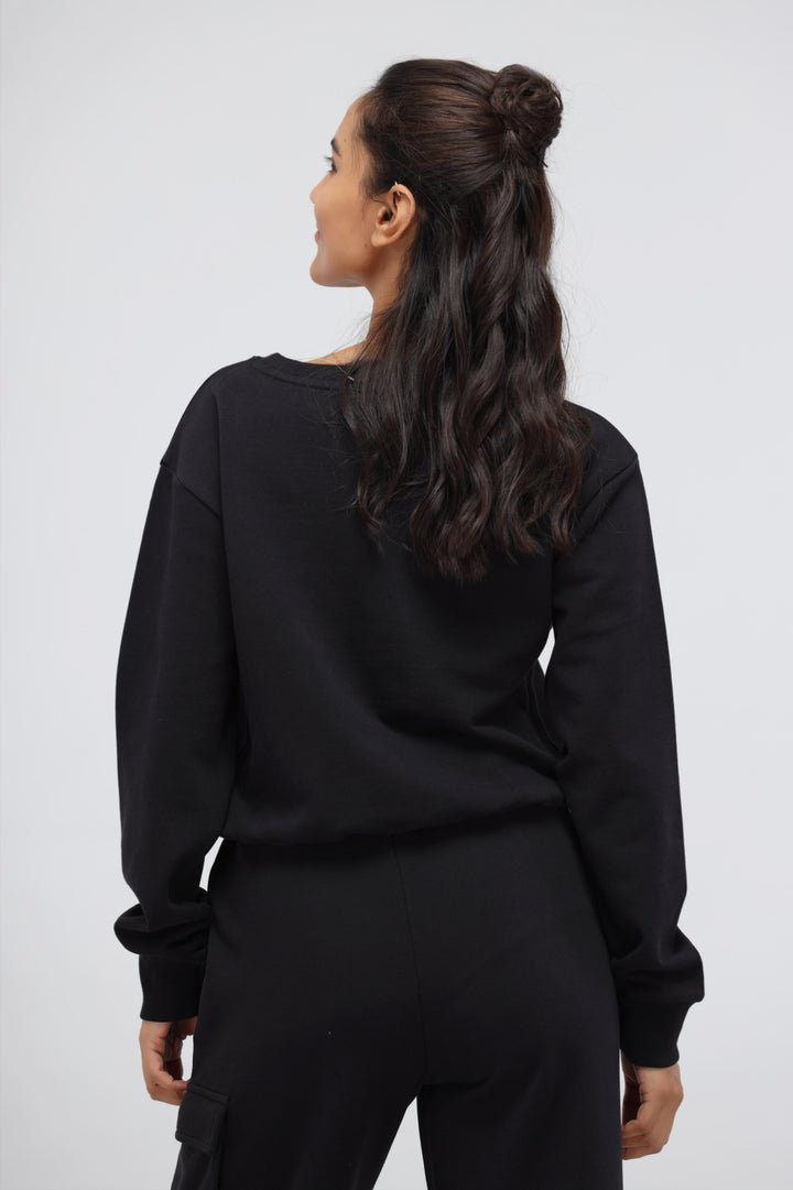 Woman wearing a jet black terry relaxed sweatshirt from the back.