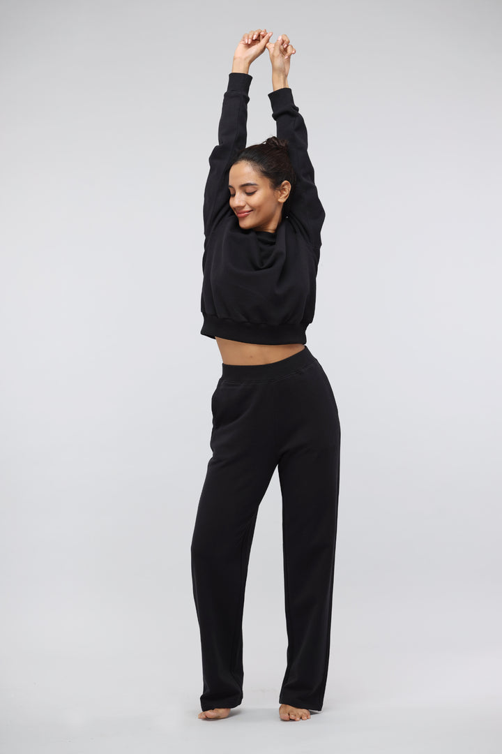 Woman wearing a Jet Black Terry Travel Set, stretching stylishly.