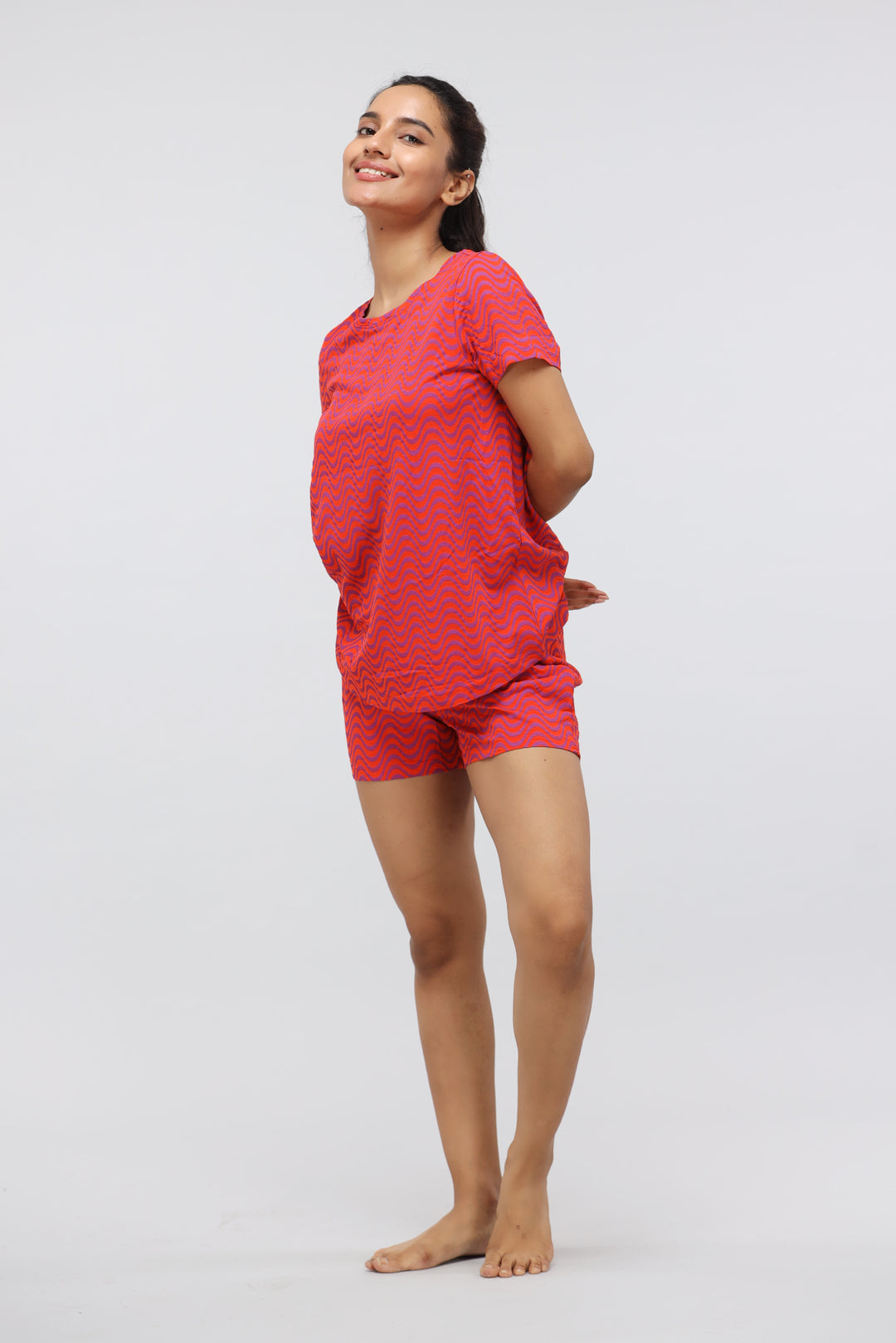 Orange wavy printed modal shorts set model smiling with hands behind back.