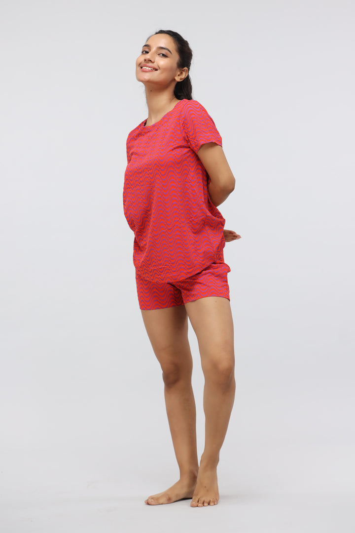 Orange wavy printed modal shorts set model smiling with hands behind back.