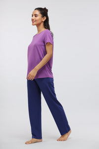 Woman wearing purple t-shirt and blue lounge pants, stylish comfort attire.
