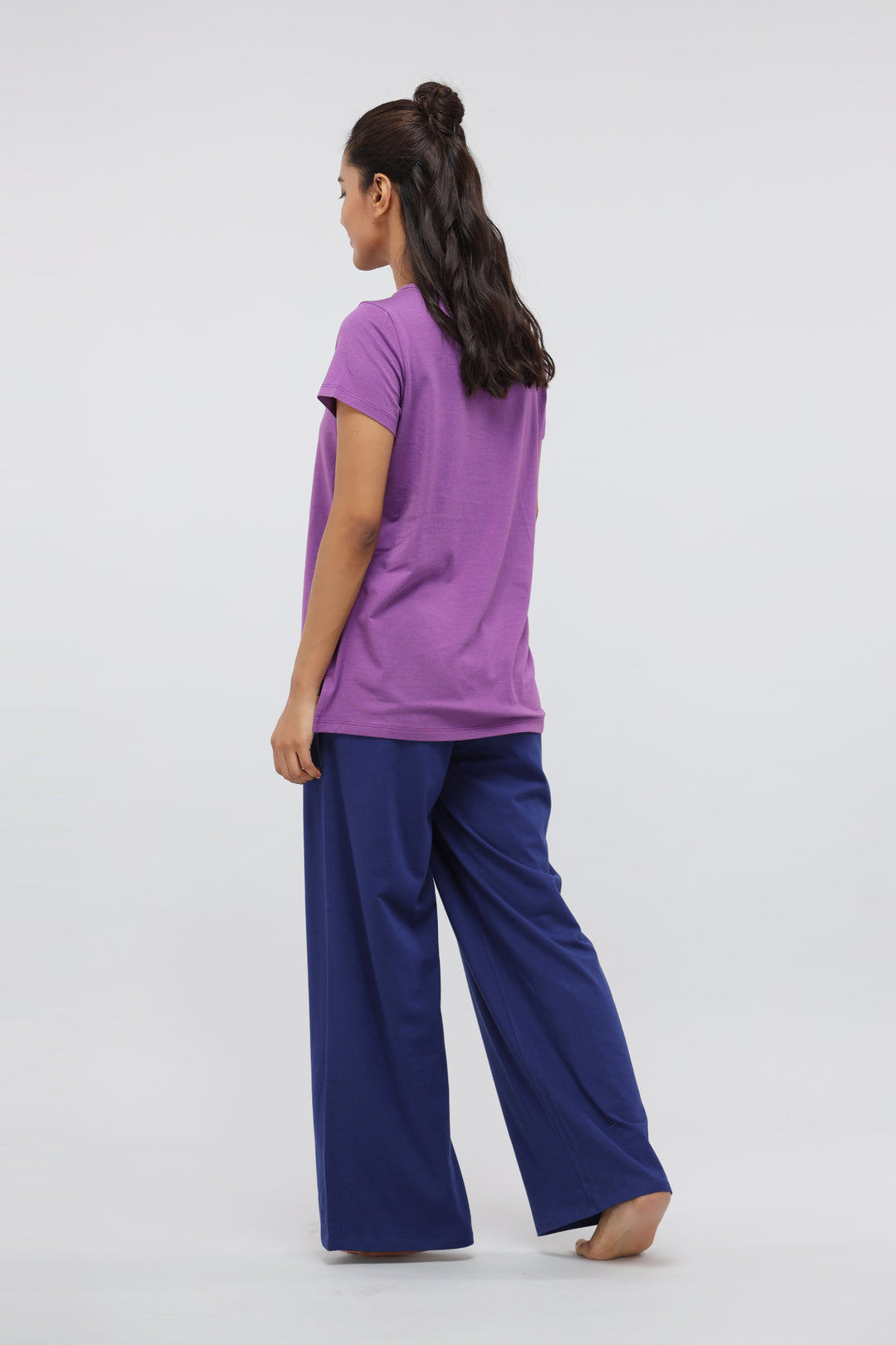 Woman in purple top and blue flared pants from lounge set.