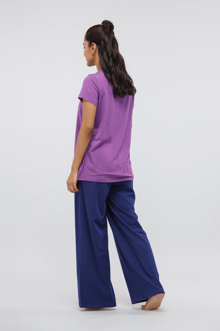 Woman in purple top and blue flared pants from lounge set.