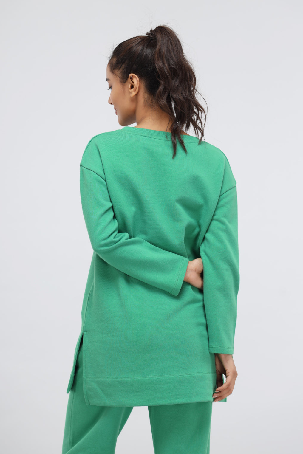Model wearing a green bee terry long pullover from the back.