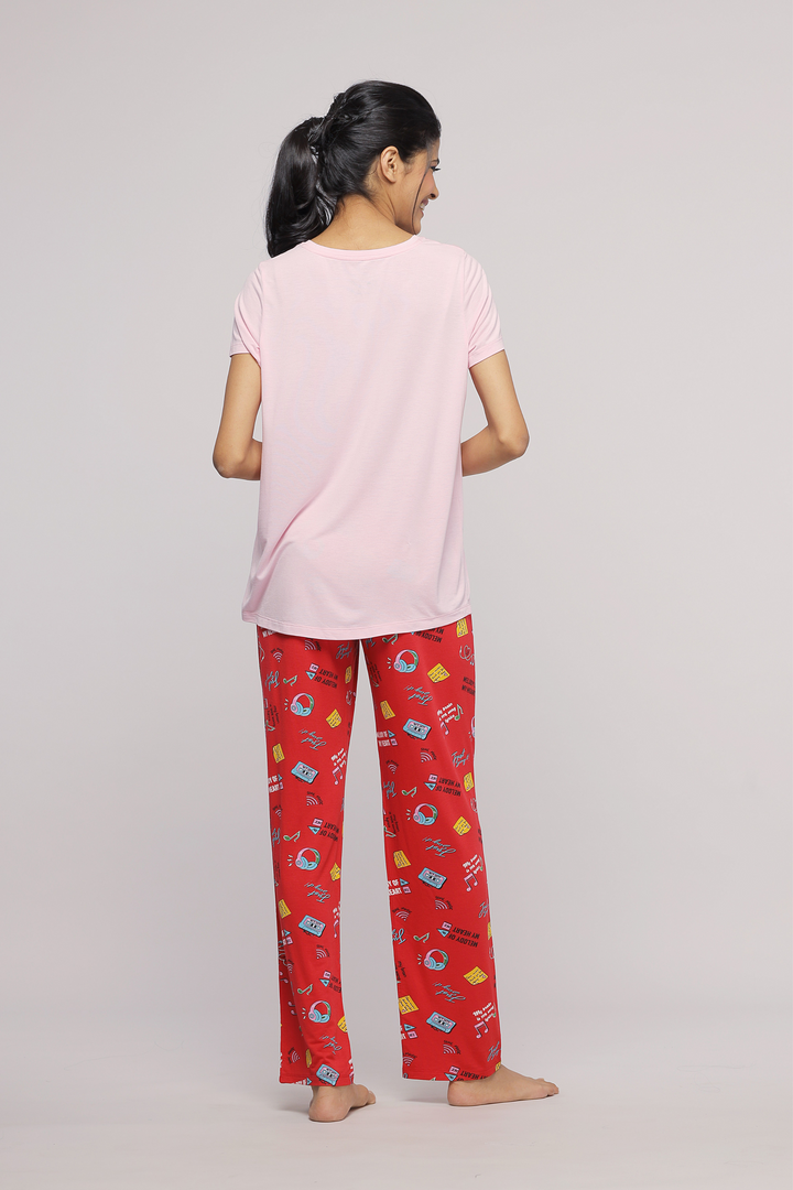 Woman wearing Pink Mist Pajama Set with playful red patterned pants.