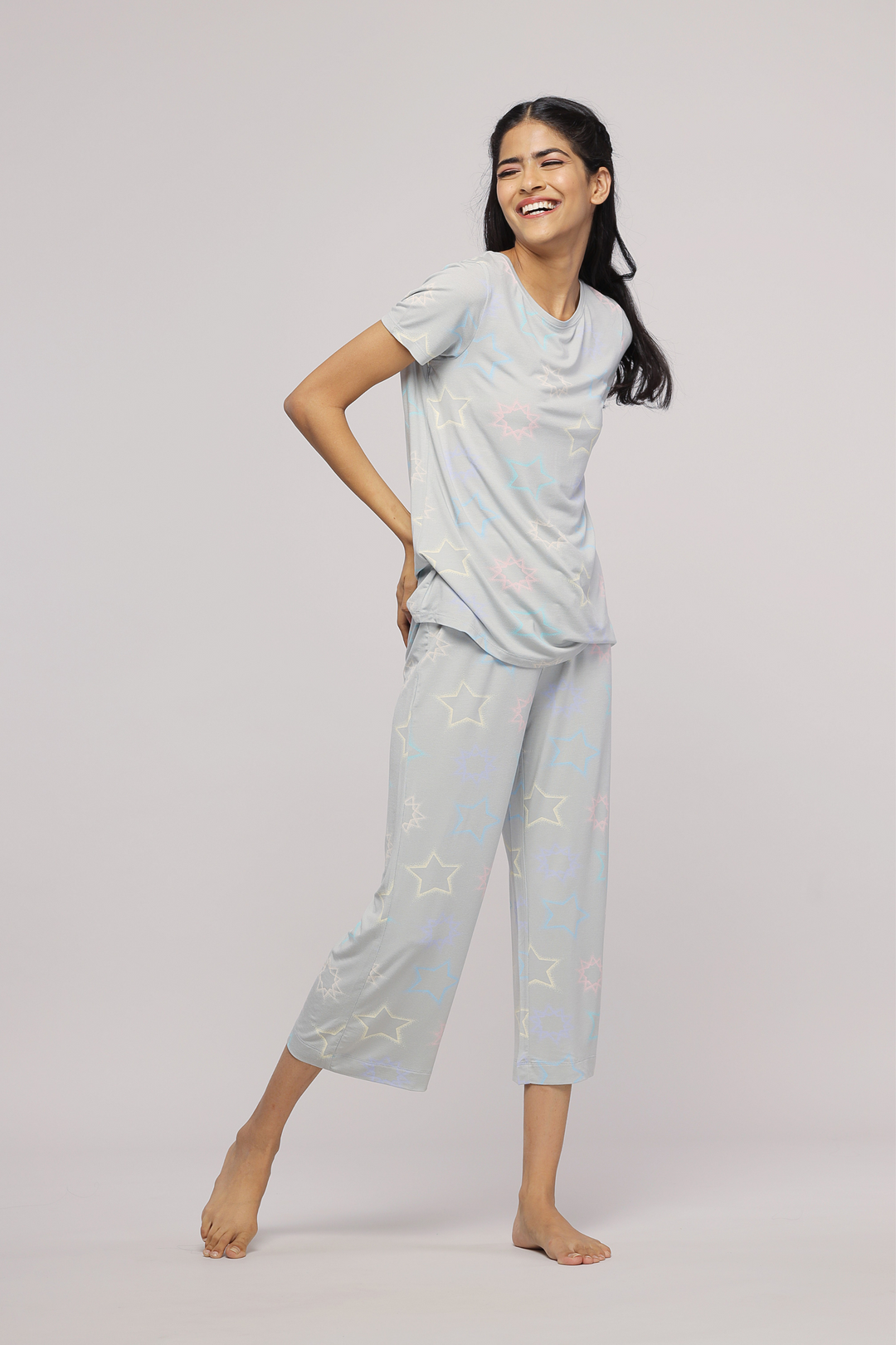 Smiling woman in Starlit Capri sleepwear with star patterns.