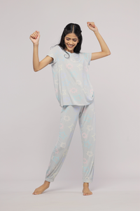 Woman in starlit cuffed pajama set, playful pose against grey background.