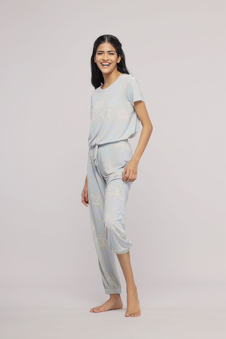 Smiling model wearing starlit cuffed pajamas in soft blue fabric.