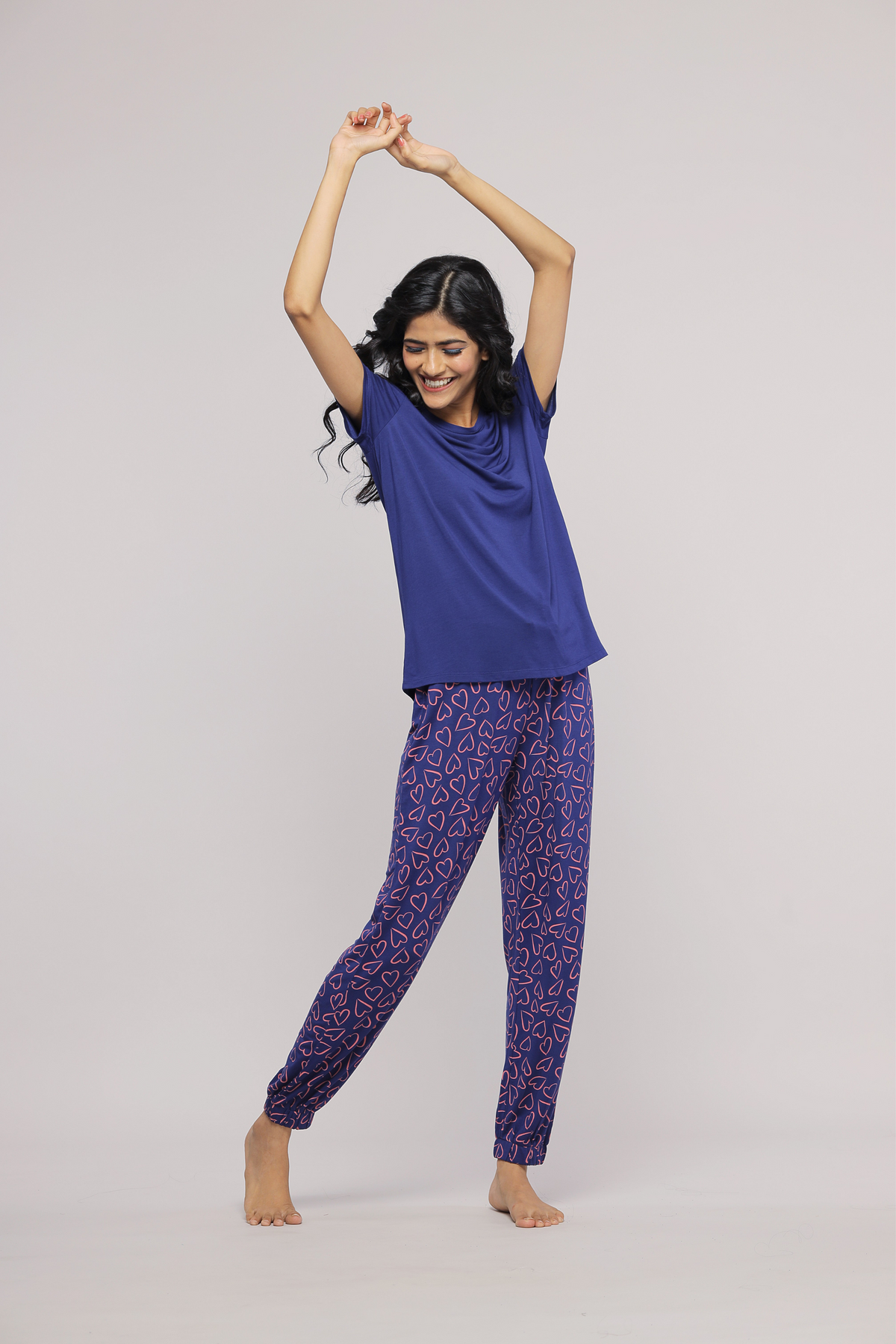 Smiling woman in Sweetheart Pajamas with heart pattern, dancing joyfully.
