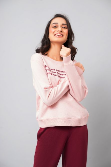 Smiling woman wearing a pink "Happy People Sweatshirt" with text design.